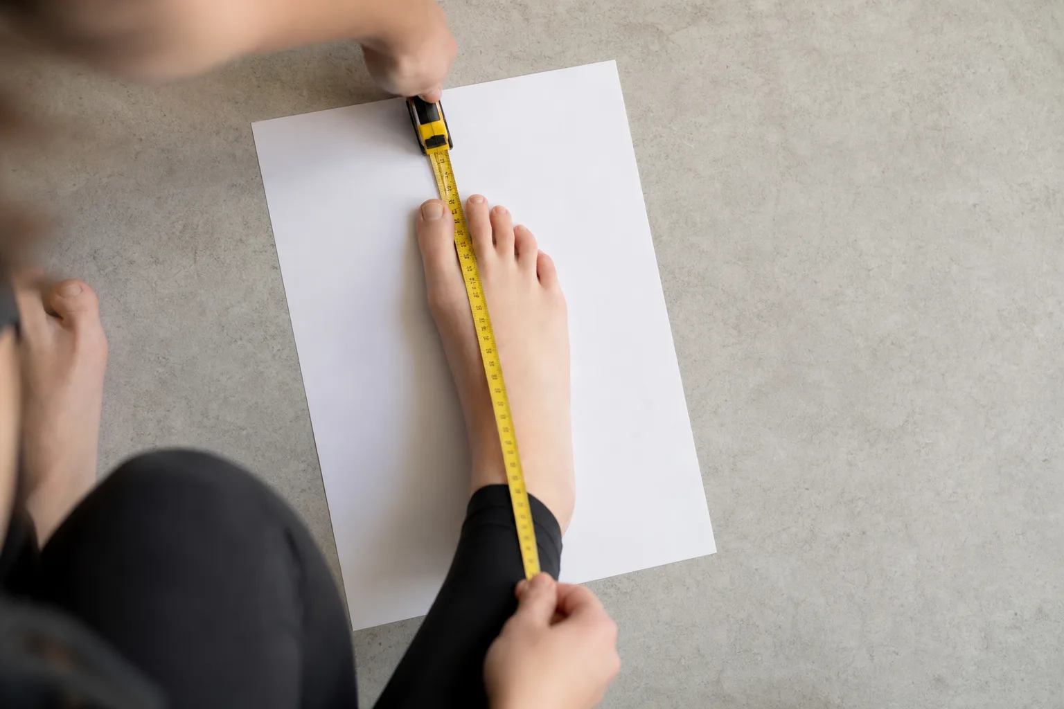 Fot mot en vägg med papper och linjal för att mäta fotlängden i centimeter
